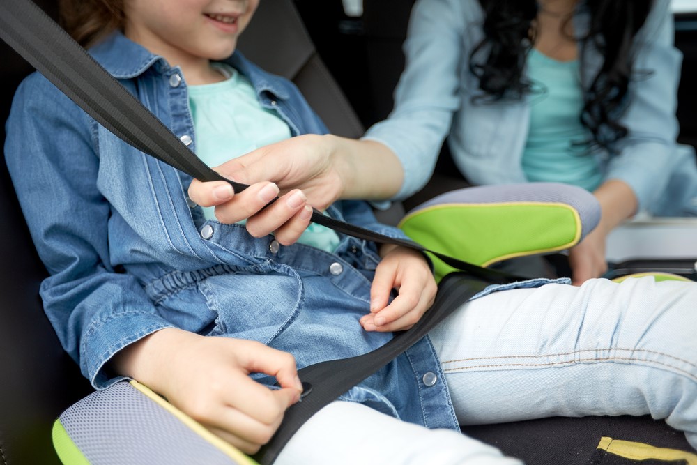 woman placing seat belt on a child